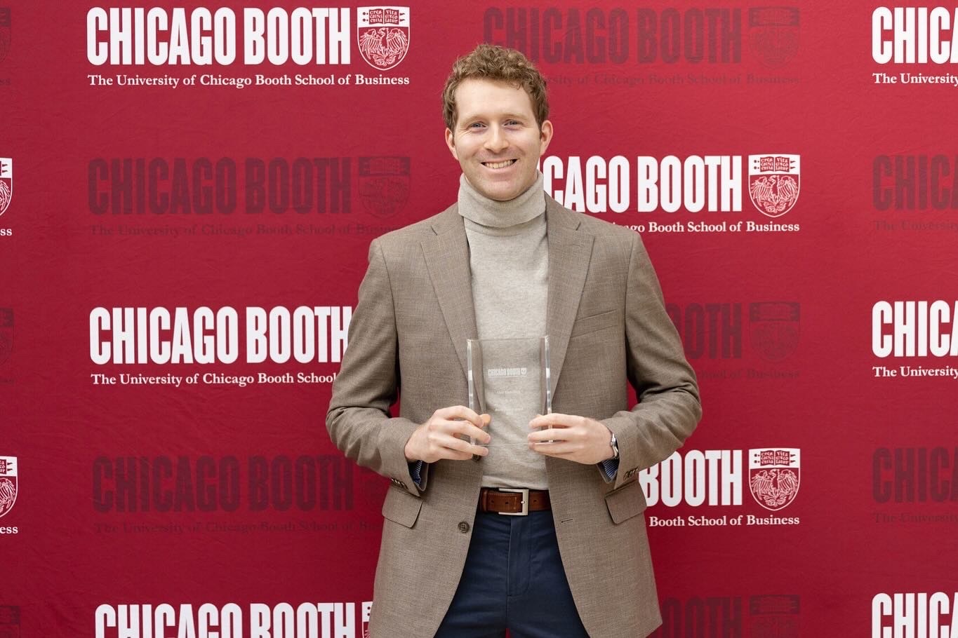 Alexander Hamilton smiling in front of a Chicago Booth backdrop